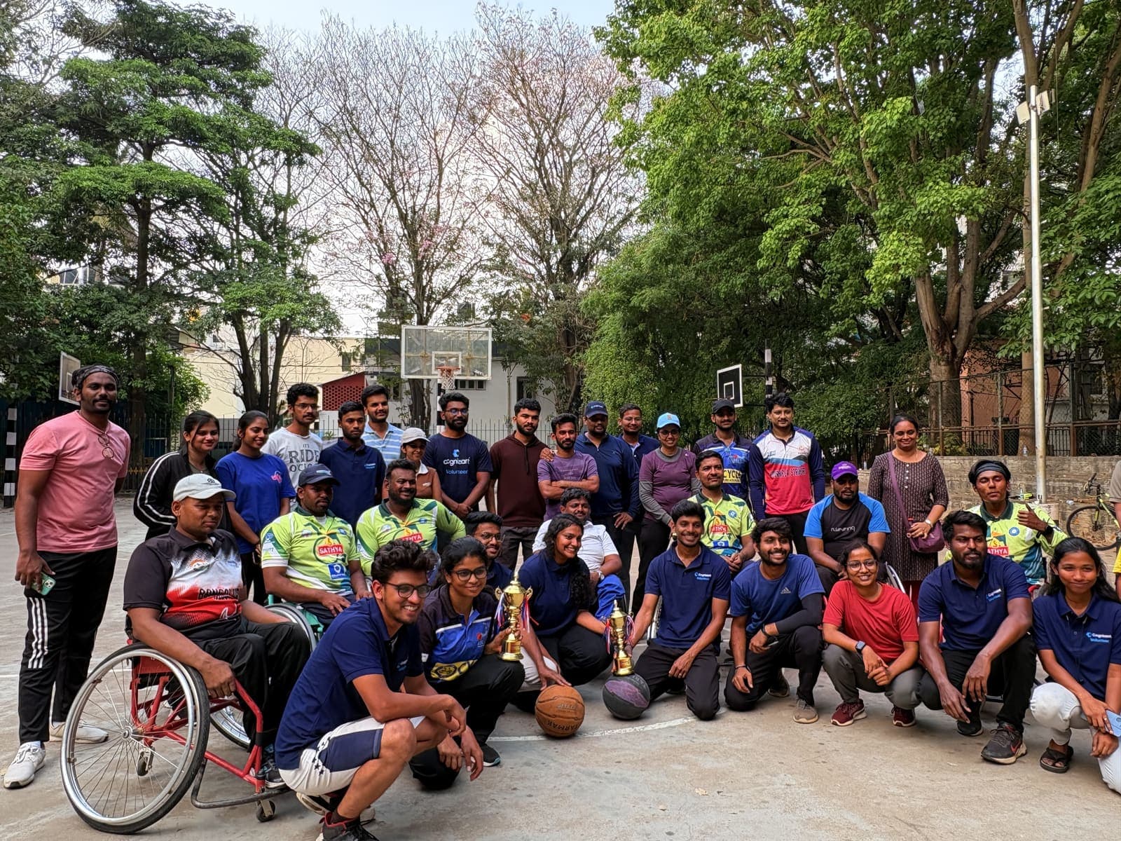DMSA volunteers and athletes together after a wheelchair basketball match, several wearing Cognizant volunteer shirts