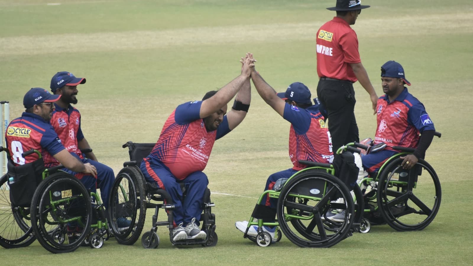 Wheelchair cricketers high-fiving on the field after a wicket